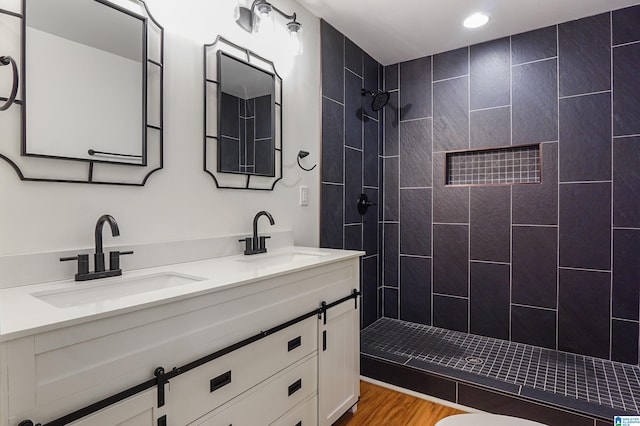 bathroom featuring vanity, hardwood / wood-style floors, and a tile shower