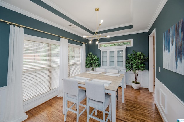 dining area with a tray ceiling, wood-type flooring, and crown molding