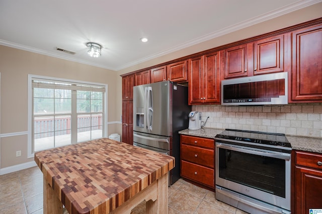 kitchen featuring tasteful backsplash, appliances with stainless steel finishes, light tile patterned floors, and ornamental molding