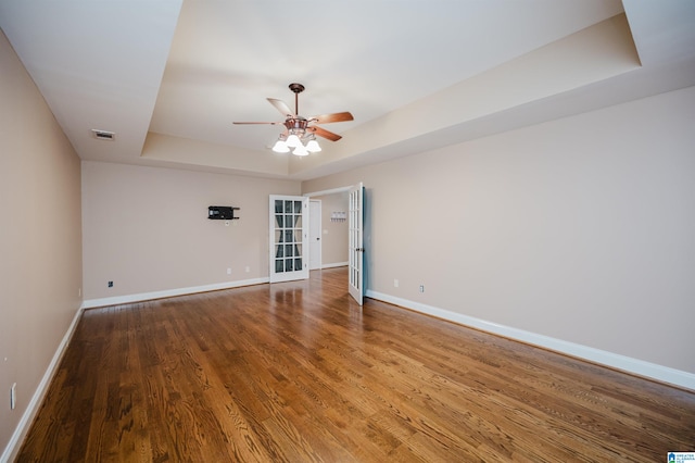 spare room featuring hardwood / wood-style floors, ceiling fan, and a raised ceiling