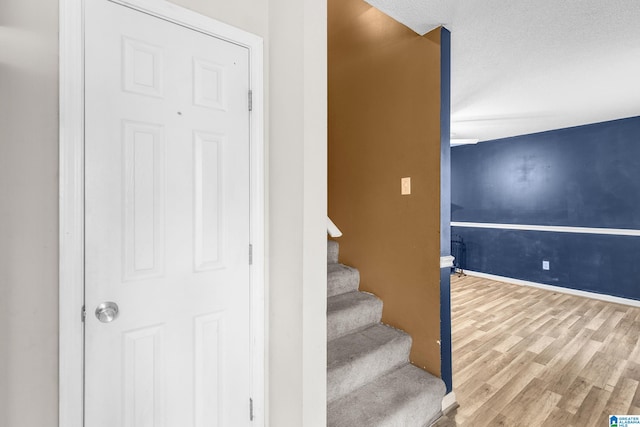 stairs featuring hardwood / wood-style floors and a textured ceiling