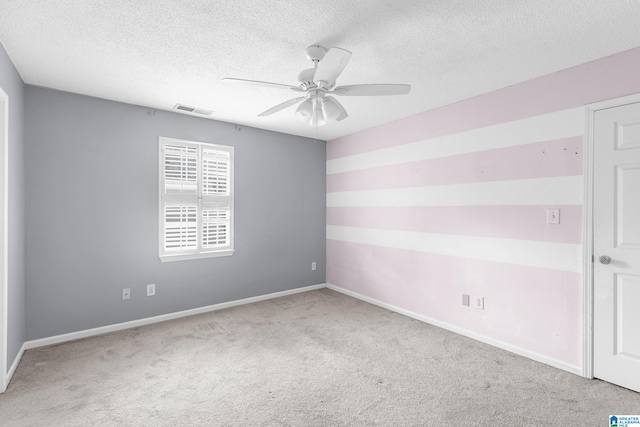 spare room with a textured ceiling, light carpet, and ceiling fan