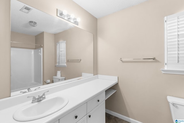 bathroom with vanity, a textured ceiling, toilet, and a shower