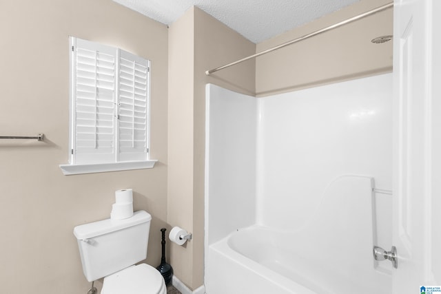 bathroom with a textured ceiling, toilet, and bathtub / shower combination