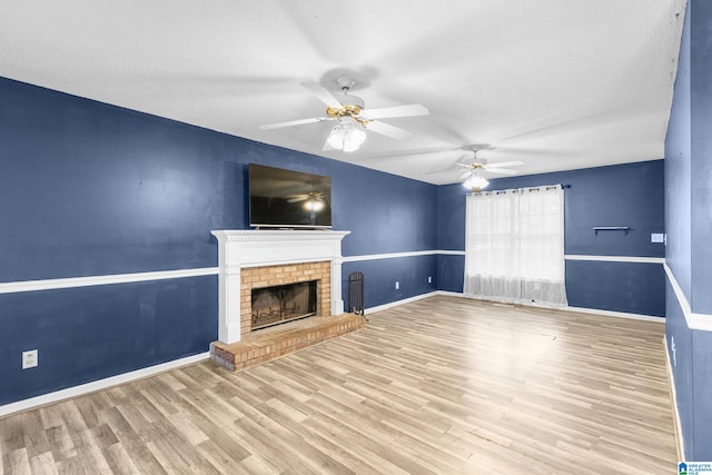 unfurnished living room featuring a textured ceiling, light wood-type flooring, a fireplace, and ceiling fan