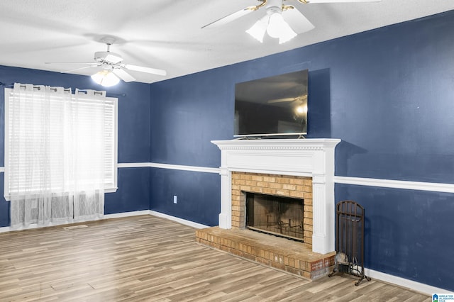 unfurnished living room with hardwood / wood-style floors, ceiling fan, a textured ceiling, and a brick fireplace