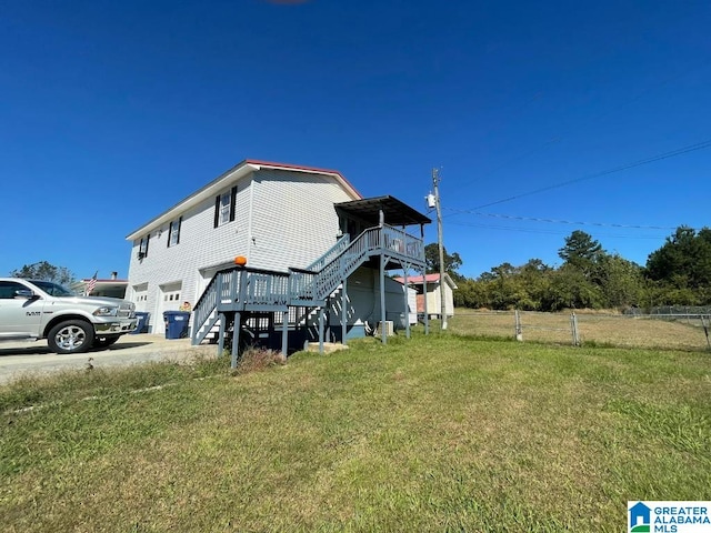 back of house featuring a lawn, a garage, and a deck