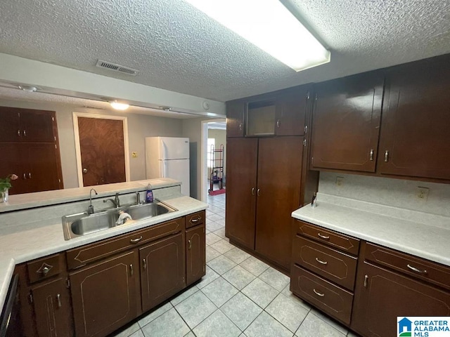 kitchen featuring dark brown cabinets, a textured ceiling, white fridge, and sink