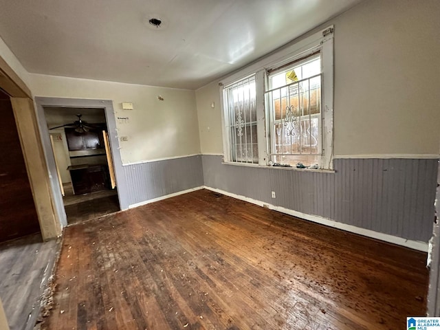 spare room featuring wooden walls, wood-type flooring, and ceiling fan