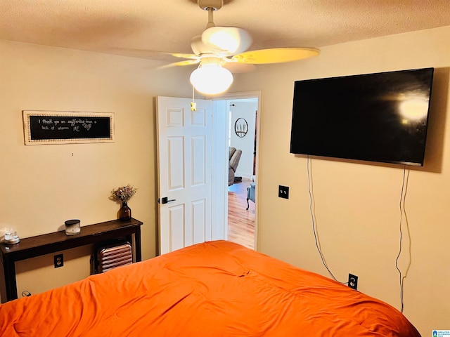 bedroom with hardwood / wood-style flooring, a textured ceiling, and ceiling fan