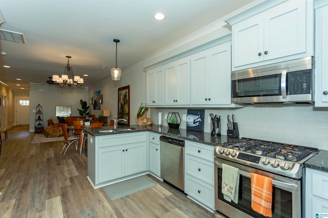 kitchen featuring light hardwood / wood-style floors, kitchen peninsula, appliances with stainless steel finishes, white cabinets, and pendant lighting