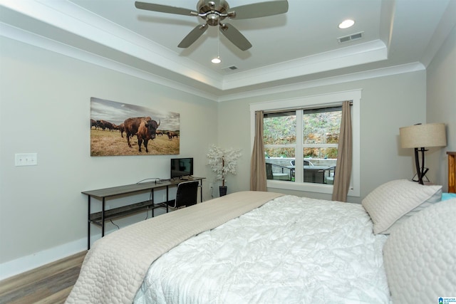 bedroom featuring hardwood / wood-style flooring, ceiling fan, crown molding, and a tray ceiling