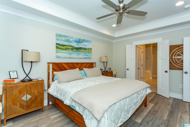 bedroom with hardwood / wood-style flooring, ceiling fan, and a raised ceiling