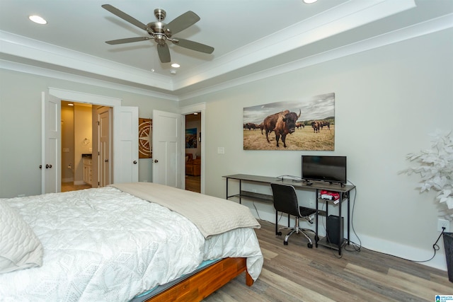 bedroom with ensuite bath, wood-type flooring, ceiling fan, and a tray ceiling