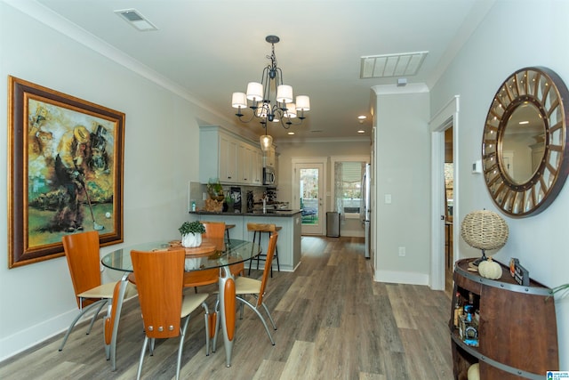 dining space featuring light wood-type flooring, a notable chandelier, and ornamental molding