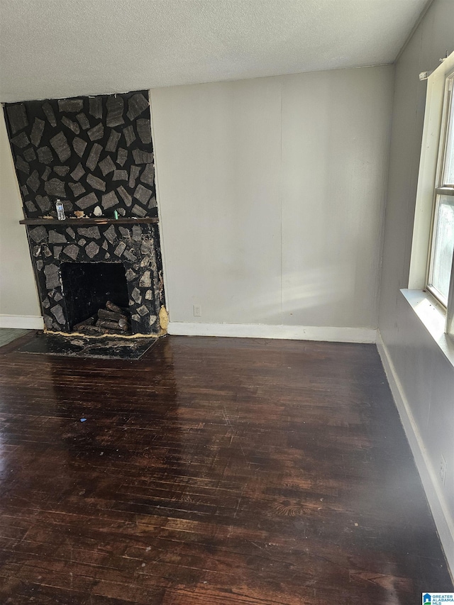 unfurnished living room featuring hardwood / wood-style floors, a textured ceiling, and a fireplace