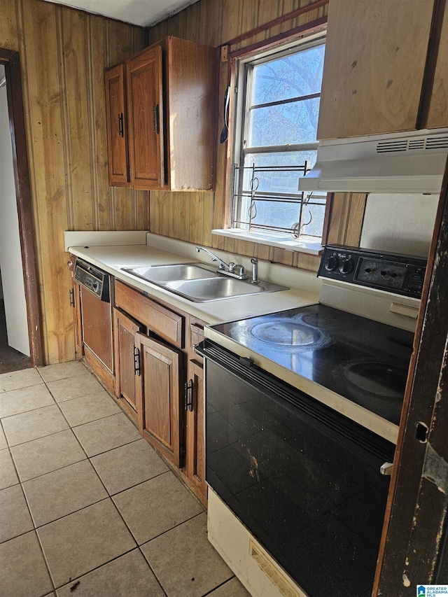 kitchen with dishwashing machine, sink, range with electric stovetop, light tile patterned flooring, and wood walls