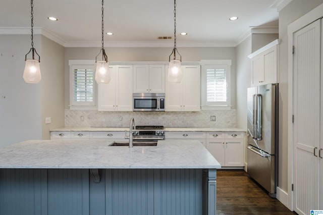 kitchen featuring premium appliances, light stone counters, hanging light fixtures, sink, and white cabinetry