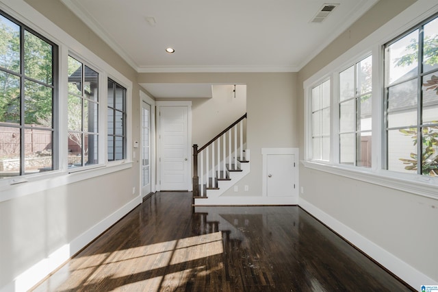 entryway with a wealth of natural light, dark wood-type flooring, and crown molding