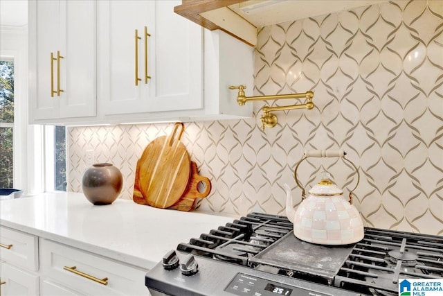 kitchen with backsplash, stainless steel range, and white cabinets