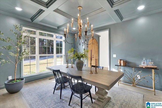 dining space with coffered ceiling, an inviting chandelier, ornamental molding, and light hardwood / wood-style flooring