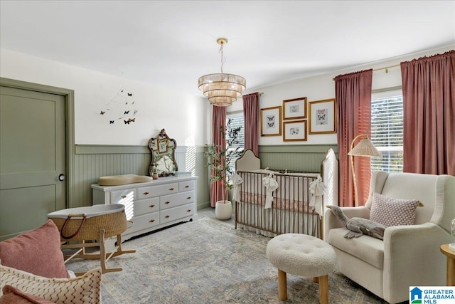 bedroom with carpet, a nursery area, and a chandelier