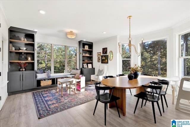 dining room featuring light hardwood / wood-style flooring, crown molding, and a notable chandelier