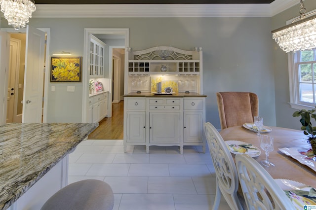 tiled dining space featuring a chandelier and crown molding