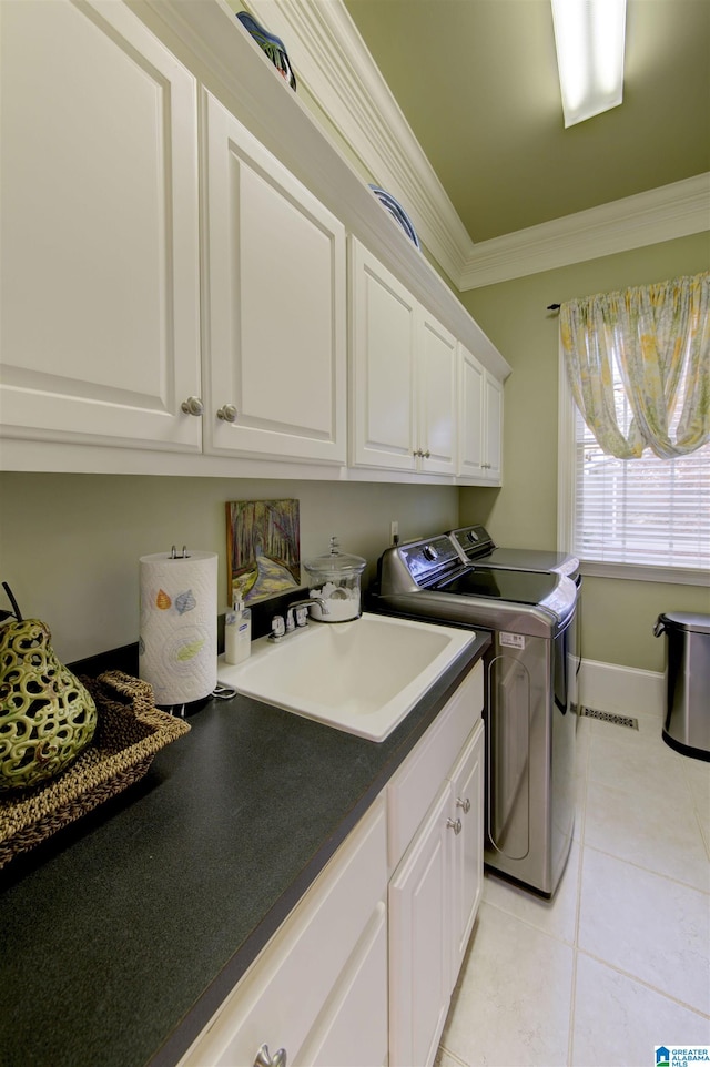 laundry room featuring cabinets, light tile patterned flooring, sink, crown molding, and washer and dryer