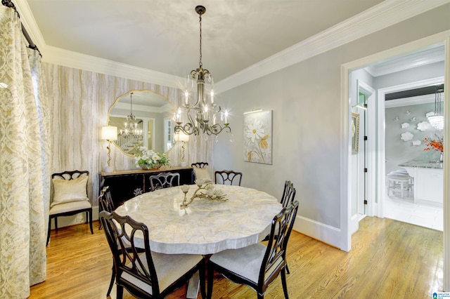 dining room with a notable chandelier, light wood-type flooring, and ornamental molding