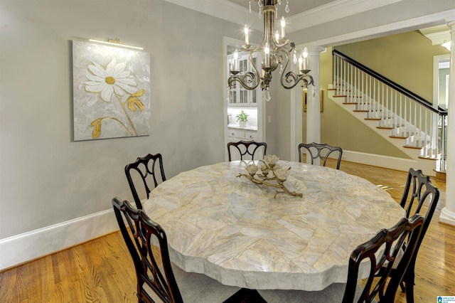 dining space featuring ornamental molding, light hardwood / wood-style floors, a notable chandelier, and ornate columns