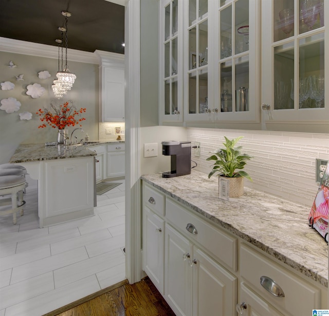 kitchen featuring white cabinetry, decorative light fixtures, backsplash, and light stone countertops