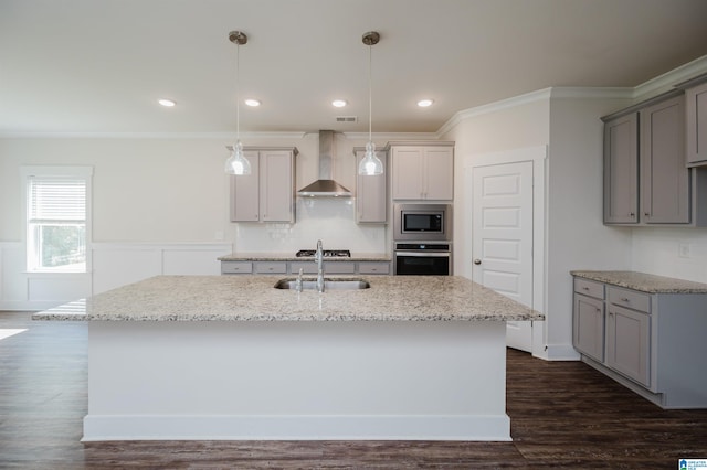 kitchen with stainless steel appliances, a center island with sink, wall chimney exhaust hood, decorative light fixtures, and dark wood-type flooring