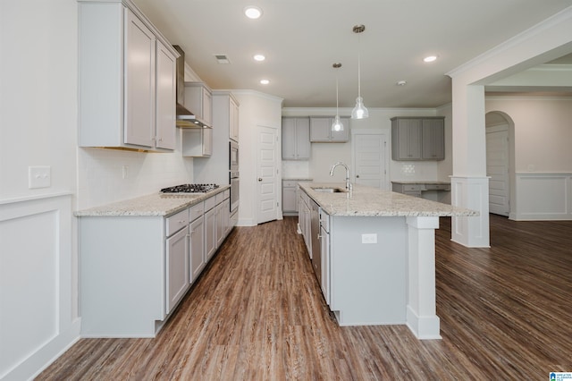 kitchen with dark hardwood / wood-style flooring, a center island with sink, sink, and ornamental molding