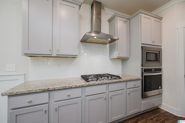 kitchen featuring stainless steel appliances, dark wood-type flooring, light stone counters, wall chimney exhaust hood, and gray cabinetry