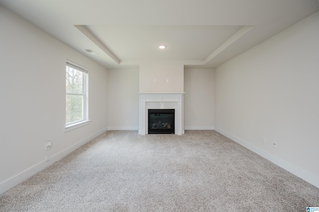 unfurnished living room featuring light carpet and a raised ceiling