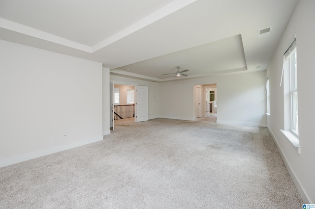 unfurnished room featuring ceiling fan, light colored carpet, and a tray ceiling