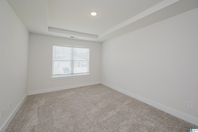 carpeted empty room with a tray ceiling