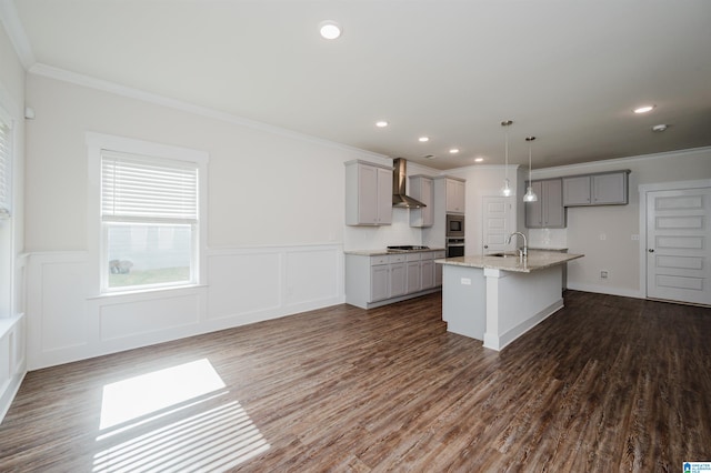 kitchen with dark wood-type flooring, a center island with sink, sink, gray cabinets, and wall chimney range hood