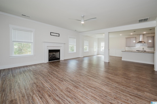 unfurnished living room with dark wood-type flooring, ceiling fan, crown molding, and sink