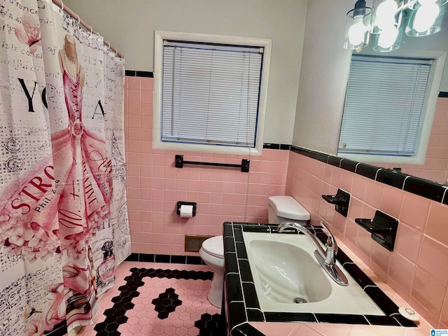 bathroom with toilet, tile walls, sink, and curtained shower