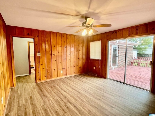 spare room with wood walls, ceiling fan, and light hardwood / wood-style flooring