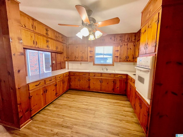 kitchen featuring ceiling fan, oven, sink, and light wood-type flooring