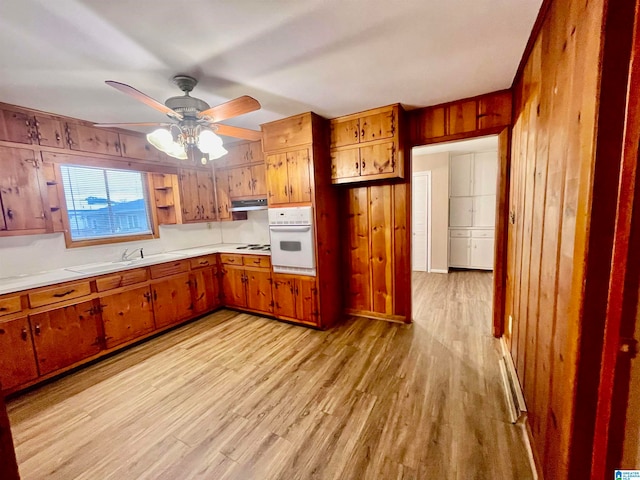 kitchen with white appliances, ceiling fan, wooden walls, and light hardwood / wood-style floors