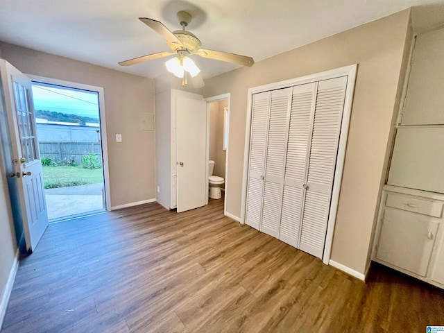 unfurnished bedroom featuring access to outside, hardwood / wood-style floors, connected bathroom, ceiling fan, and a closet