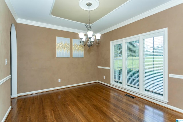 empty room featuring wood-type flooring, a chandelier, and crown molding