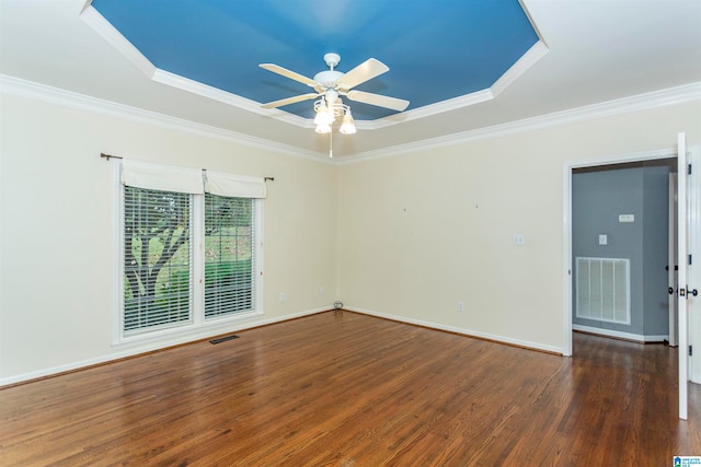 spare room featuring ceiling fan, dark hardwood / wood-style floors, crown molding, and a tray ceiling