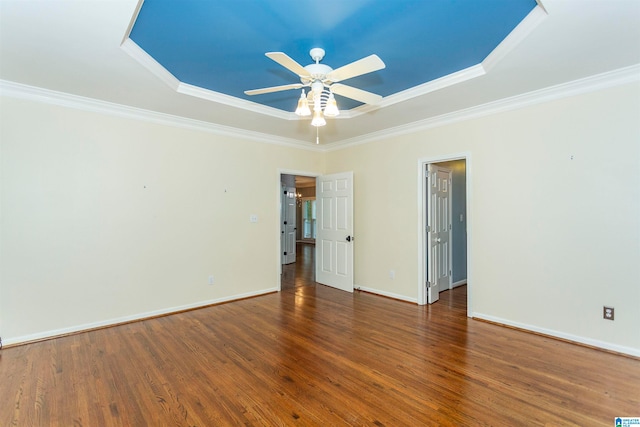 unfurnished room with dark wood-type flooring, a tray ceiling, and ornamental molding