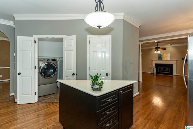 kitchen featuring washer / clothes dryer, hanging light fixtures, crown molding, a center island, and dark wood-type flooring