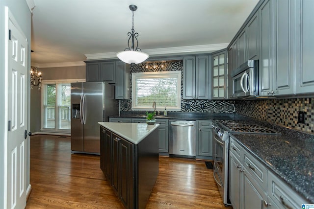 kitchen with appliances with stainless steel finishes, dark wood-type flooring, a center island, and decorative light fixtures